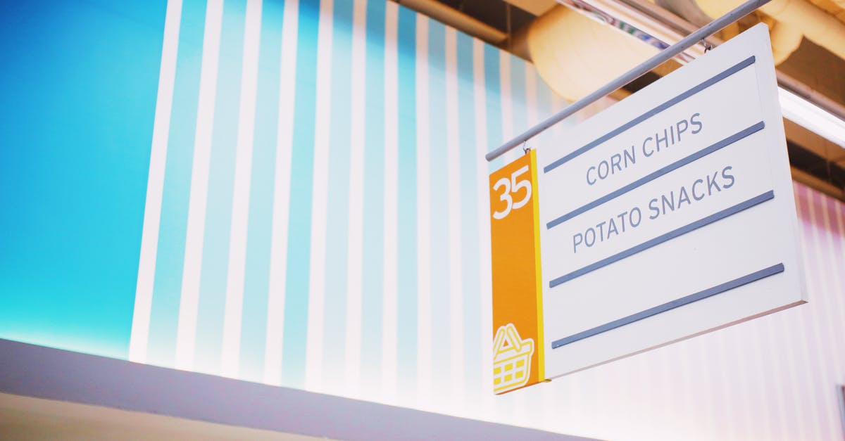 What properties did Disney buy from 21st Century Fox? - From below of signboard with inscription Corn chips Potato snacks hanging under ceiling in contemporary supermarket