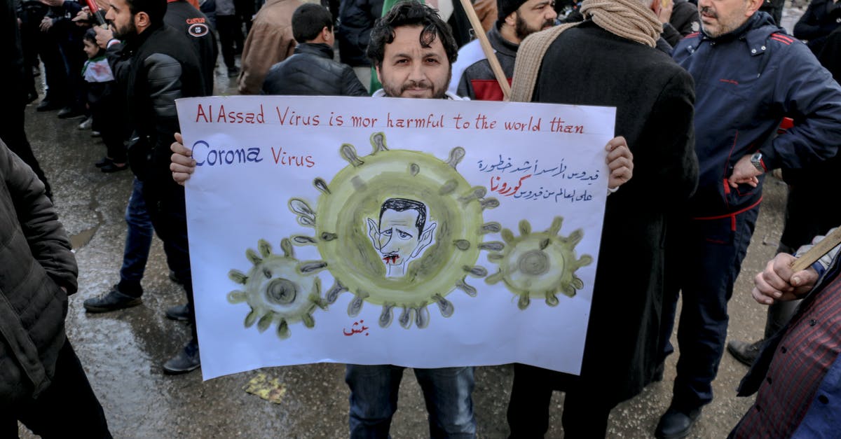 What stops government from turning off the feeds? - High angle of ethnic male activist with poster standing on crowded street at demonstration against policy