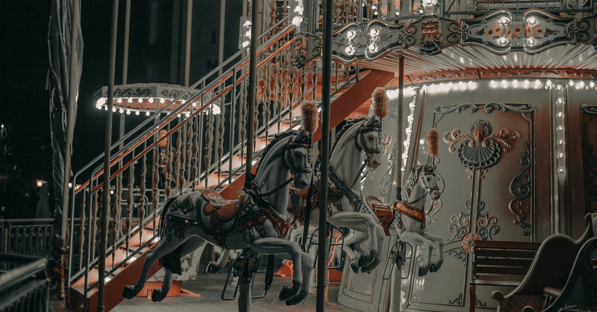 What was going on in the town after dark in 1917? - Glowing carousel with white horses and stairs with railing with ornamental elements at funfair at night