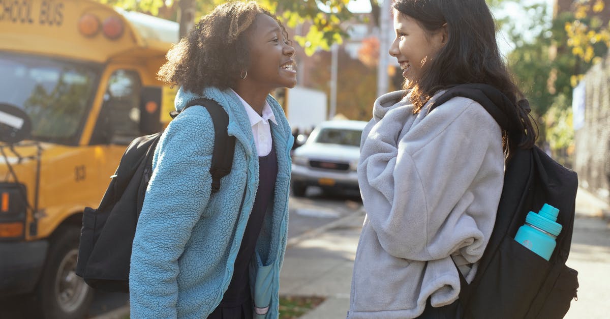 What was the conversation in French, American Crime Season 2 - Side view happy multiracial schoolgirls in warm jackets with backpacks standing on street near school bus and talking while looking at each other with smile