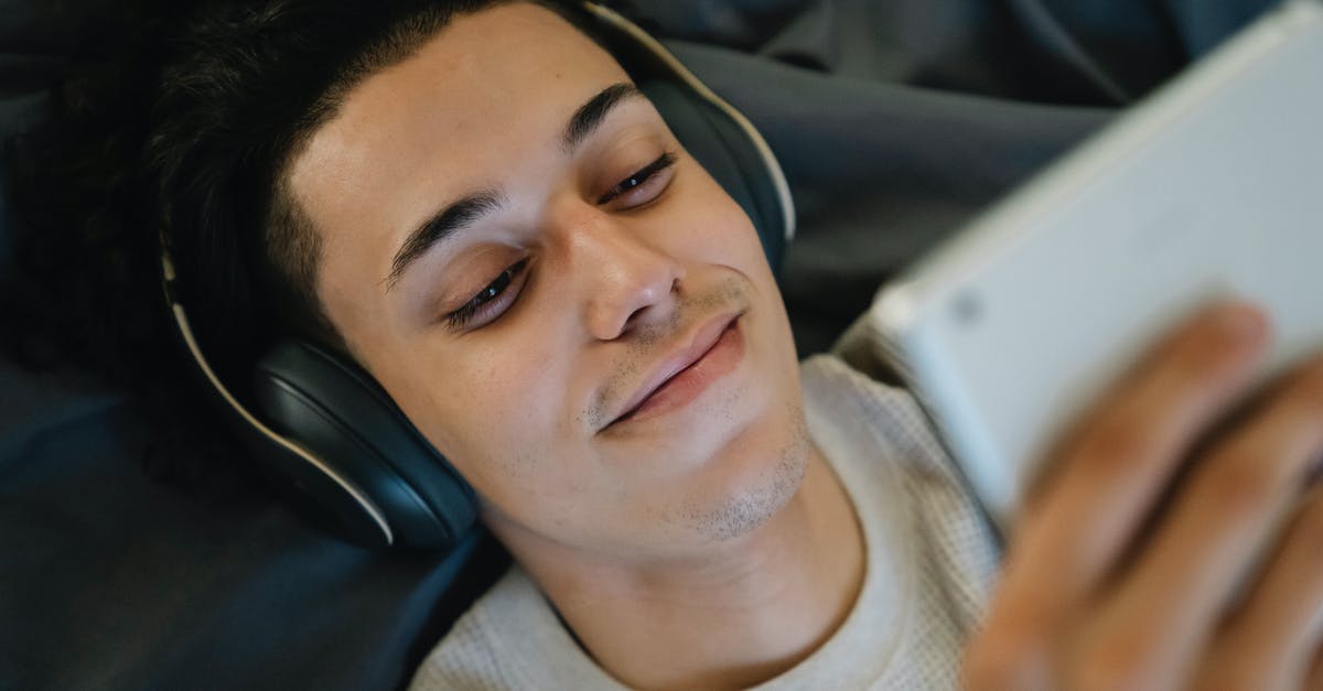 What was the end conclusion for the movie The Man From Earth - Positive young Hispanic man in headphones smiling and watching film on tablet while relaxing on bed at home