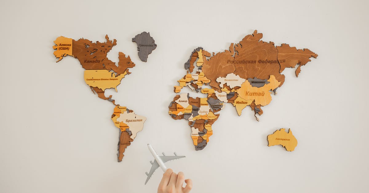 What was the name of the 'visitor' race? - Crop unrecognizable person with toy aircraft near multicolored decorative world map with continents attached on white background in light studio