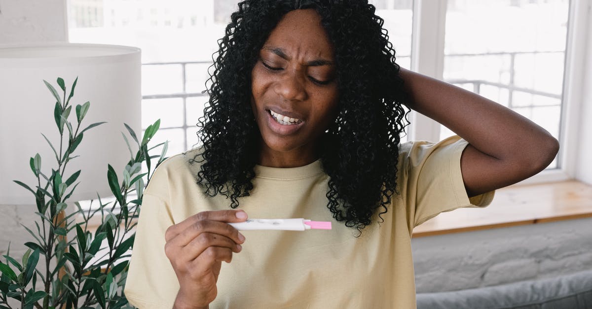 What was the result of Erica's HIV test? - Frustrated African American female in casual clothes looking at pregnancy test in hand while standing in light living room at home