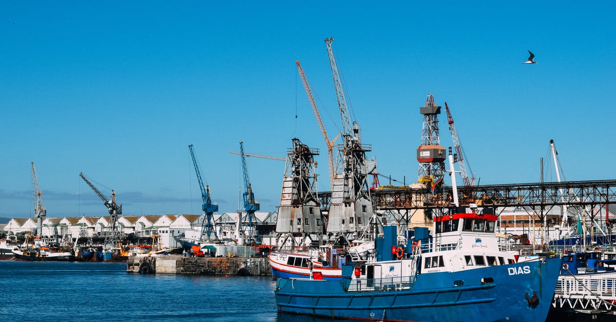 What was the ship under construction initially called? - Industrial dock with contemporary cranes and moored cargo vessels in blue water in sunlight