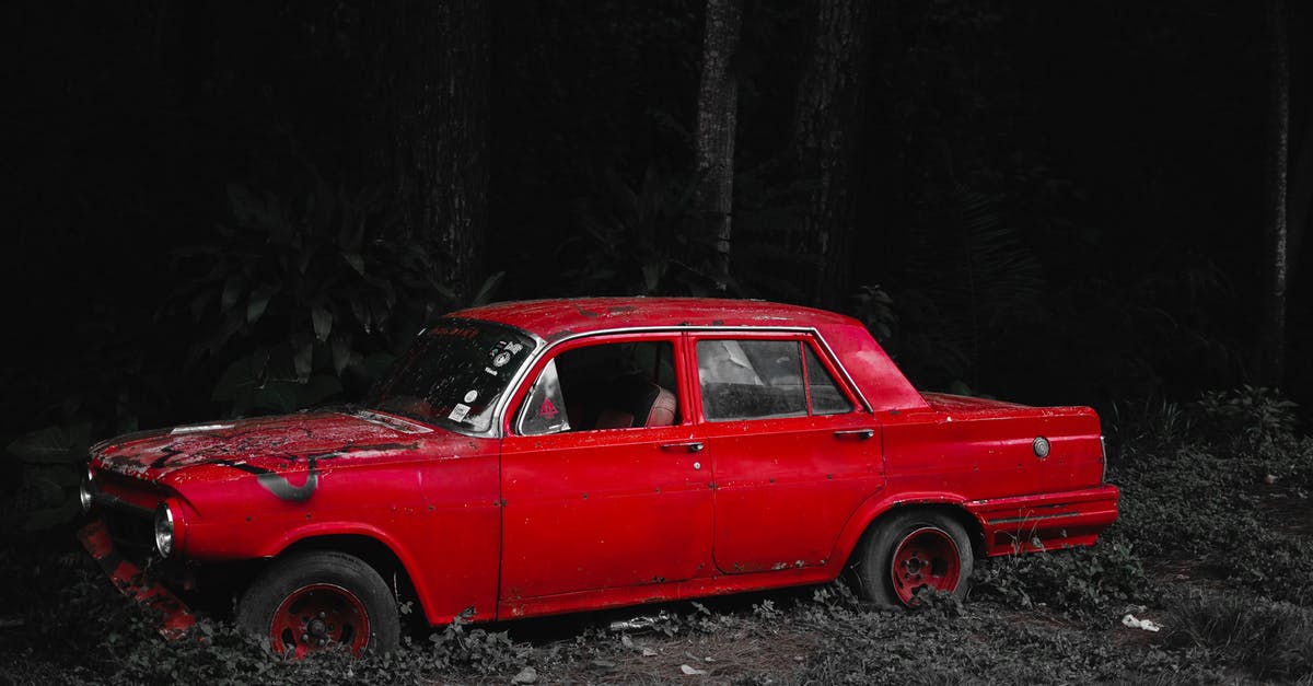 What was the significance of the tire iron? - Old car with damaged bumper and broken window on grassy ground in forest