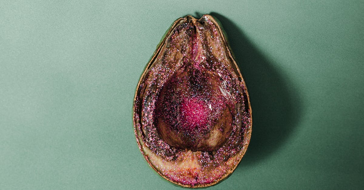 What was with the rotten fruits? - From above of half of rotten avocado covered with pink glitter placed on green background in studio