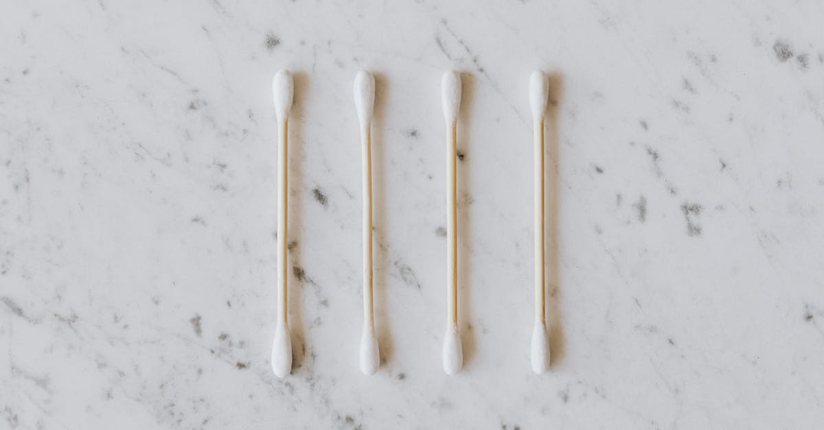 When did Chris stuff his ear with cotton? - Top view of identical cotton swabs on thin wooden sticks with soft rounded edges on marble surface with tiny spots and gray lines