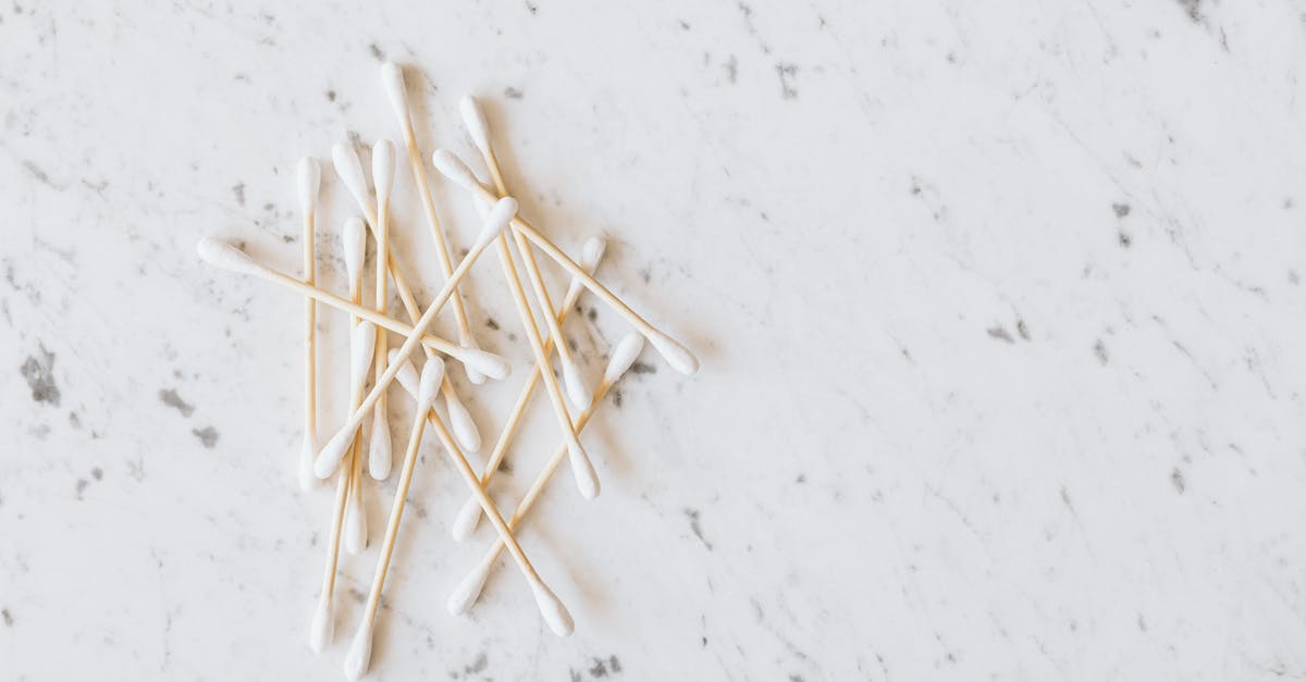 When did Chris stuff his ear with cotton? - From above of heap of similar cotton swabs on thin wooden sticks with soft edges on marble surface with grey lines