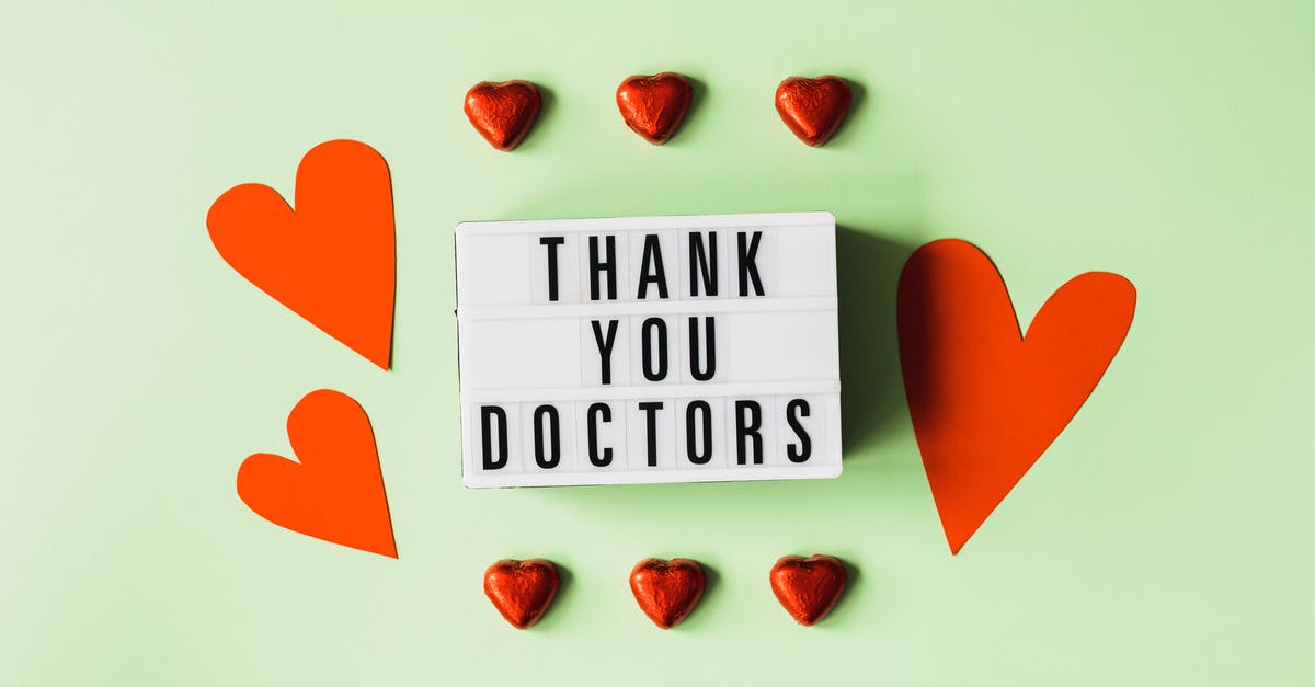 When did this character have a change of heart? - Top view of red heart shaped decorative elements and white retro light box with THANK YOU DOCTORS gratitude message arranged on green background