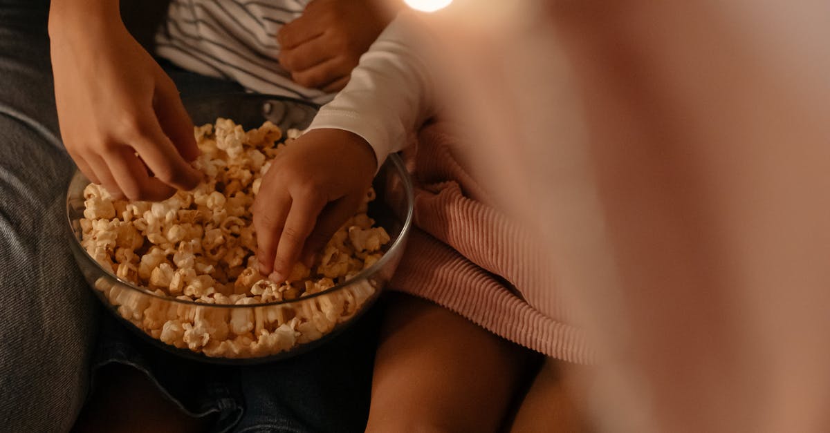 When the kids were getting attacked couldn’t they just leave the game? - Photograph of Kid's Hands Getting Popcorn From a Bowl