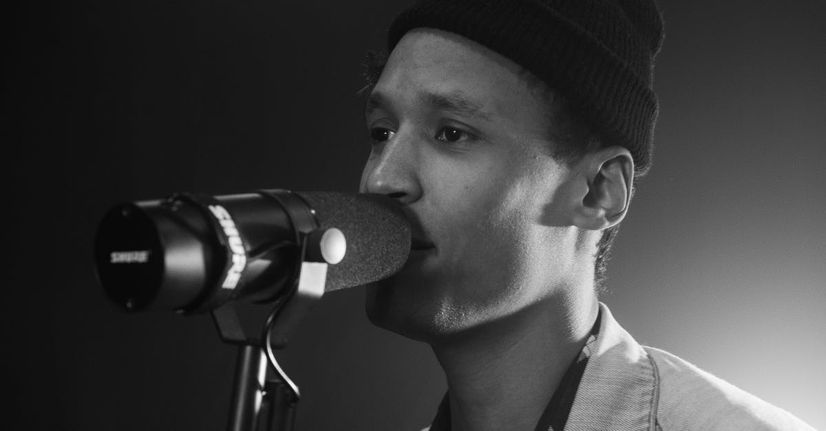 When the singing voice is also the regular voice - Grayscale Photo of a Man with a Beanie Singing on a Microphone