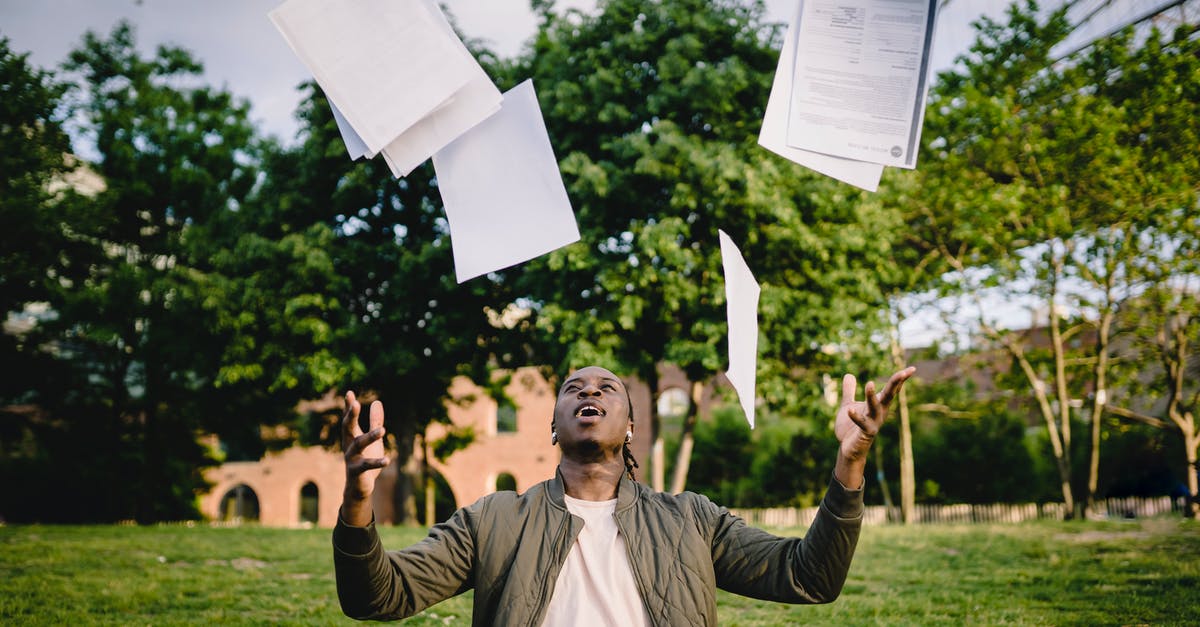 Where'd this guy get a grenade? - Overjoyed African American graduate tossing copies of resumes in air after learning news about successfully getting job while sitting in green park with laptop