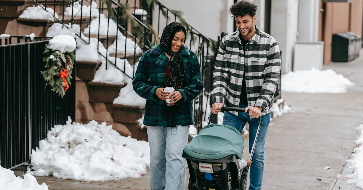 Where did Morra go for a holiday? - Positive ethnic couple having stroll with baby in stroller