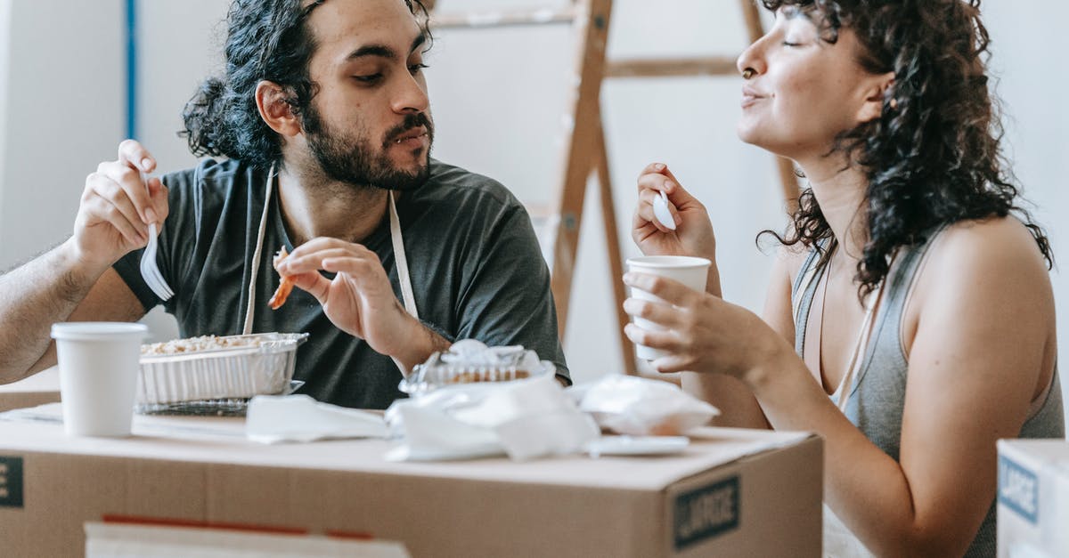 Where did the box go? - Ethnic couple enjoying delicious takeaway lunch in renovated house