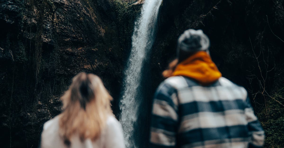Where did the ninjas come from? - Unrecognizable Couple Looking at Waterfall Coming from Rock