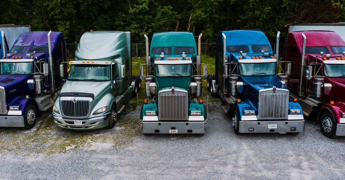 Where did the story-line of Warehouse 13 and The Librarians originate? - Row of vintage classic trucks of different colors parked on roadside outside warehouse against lush trees