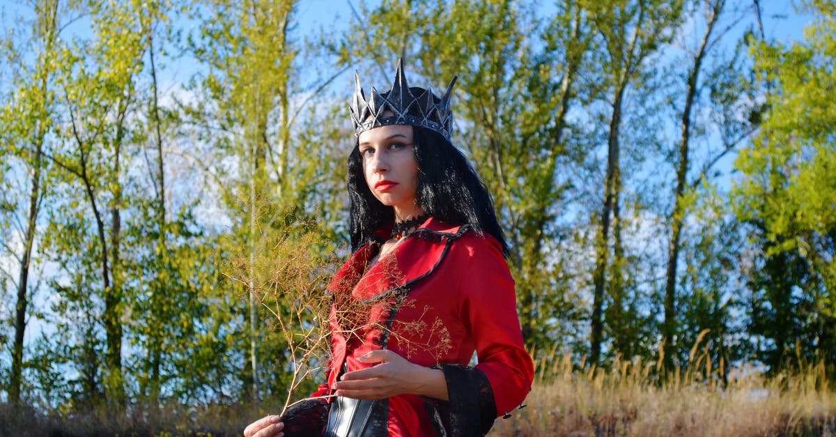 Where did the worm that appeared in the black goo chamber come from? - From below of serious young female wearing costume of witch queen with crown standing near trees and plants and looking at camera