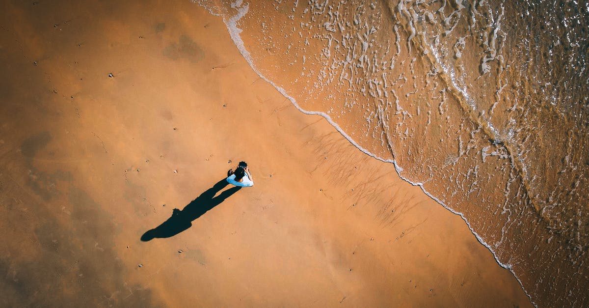 Where were the shootings done from in Jack Reacher? - Aerial view of unrecognizable male tourist launching drone standing on sandy beach near wavy sea on sunny day
