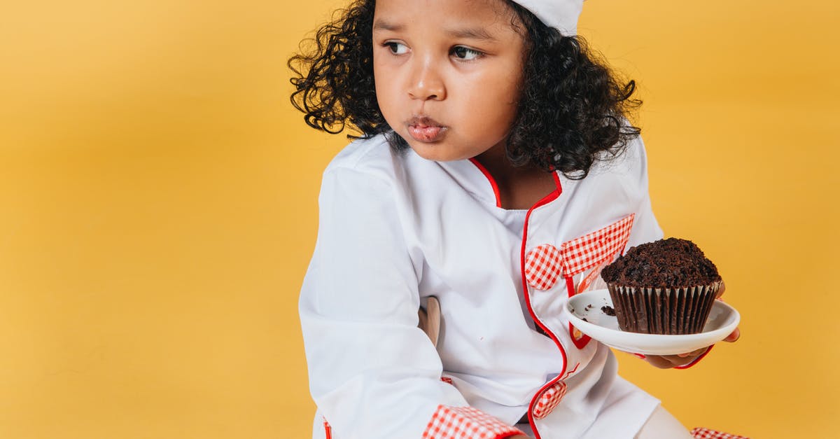 Which came first - Chef's Chocolate Salty, or Schweddy Balls? - Adorable African American girl in chef uniform and hat eating muffin against yellow background