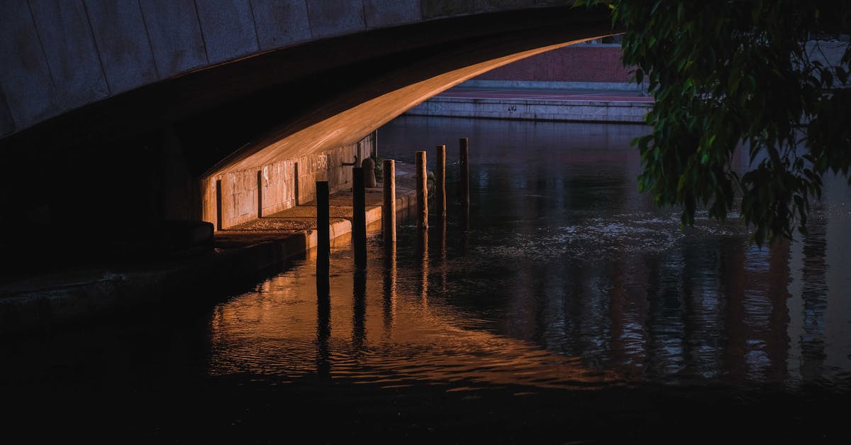 Which episodes of Flash cross over with Arrow? - Narrow space and enclosure under concrete bridge over calm rippling river in dusk
