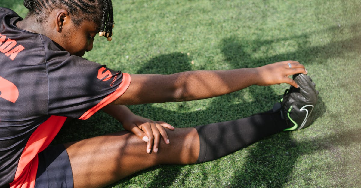 Which level player is Parzival in Ready Player One? - From above of black female soccer player sitting on green grass and stretching before coming on field