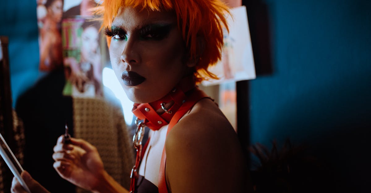 Which Marvel character is "some guy from Egypt"? - Side view of serious transsexual ethnic male with eccentric makeup in orange wig and BDSM collar standing in dressing room and looking at camera