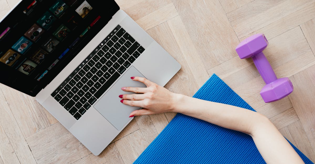 Which movie did top-to-bottom credits first? - Top view of crop anonymous female looking for video workout courses on laptop while sitting on blue yoga mat with purple dumbbell beside on parquet floor