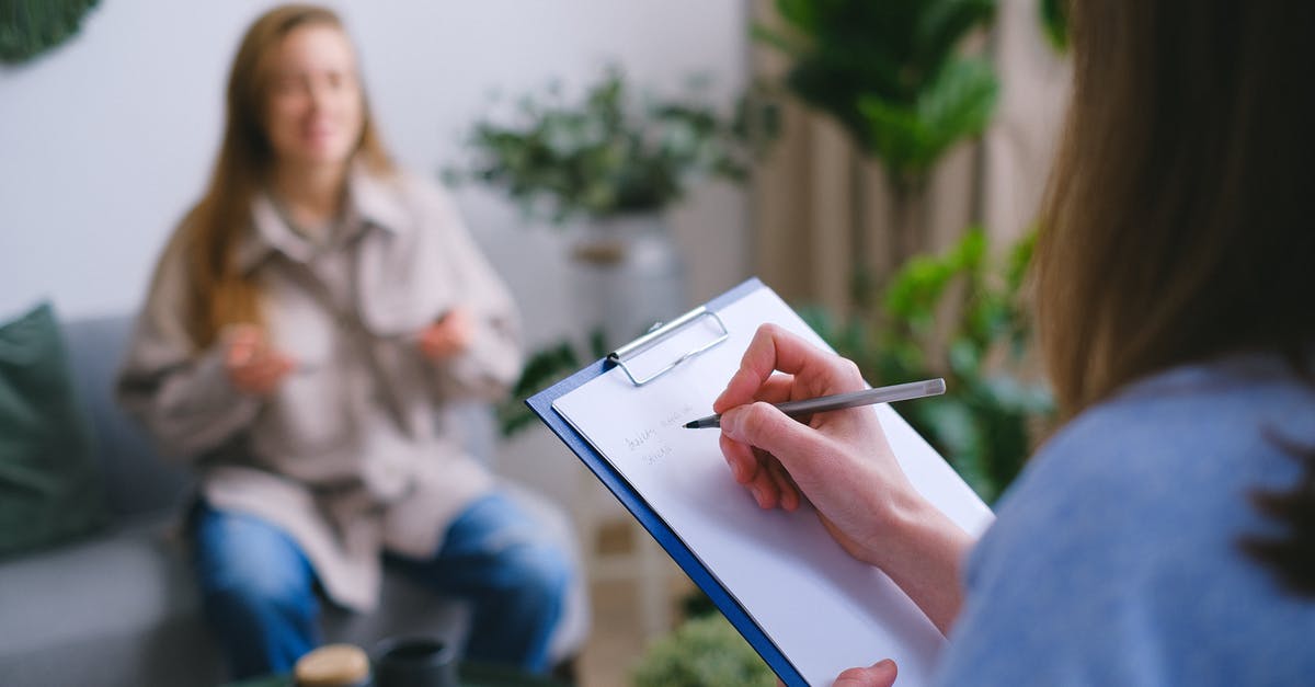 Who are these ghosts that visit Dan? - Unrecognizable professional female psychologist writing on clipboard while sitting against client on blurred background during psychotherapy session in light office