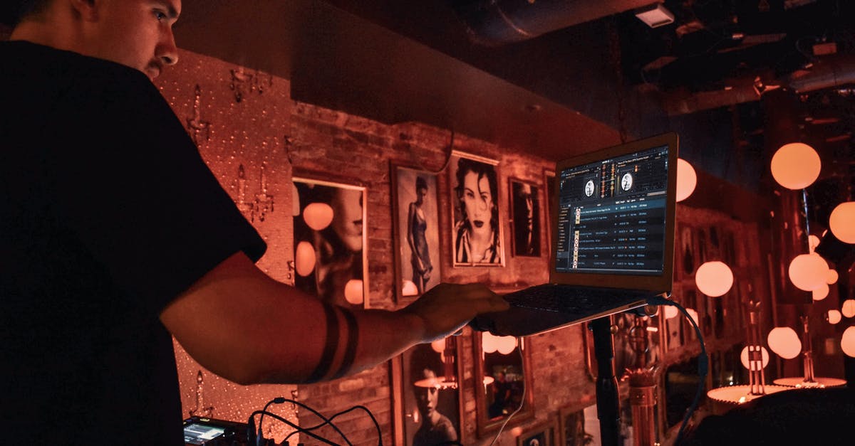 Who is the guy in the Picture in Naked Gun 2 1/2 "Blue Note" jazz bar scene? - Male DJ in black tee shirt standing behind equipment and selecting songs on laptop during party in bar