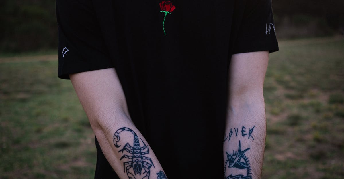 Who is the guy with the roses and what is he doing? - Crop tattooed man chilling in nature at sundown