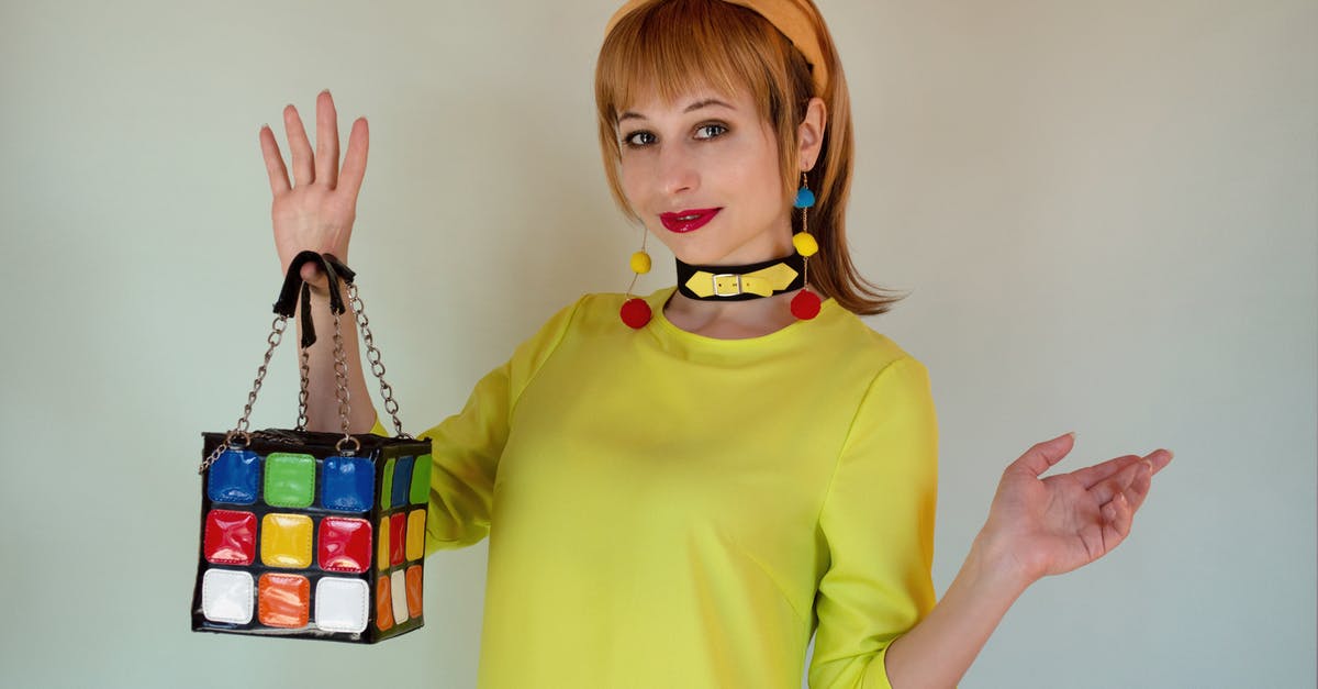 Who is the lady in Cube 2? - Stylish female in trendy yellow outfit with headband and colorful bijouterie with multicolored cube handbag looking at camera on white background