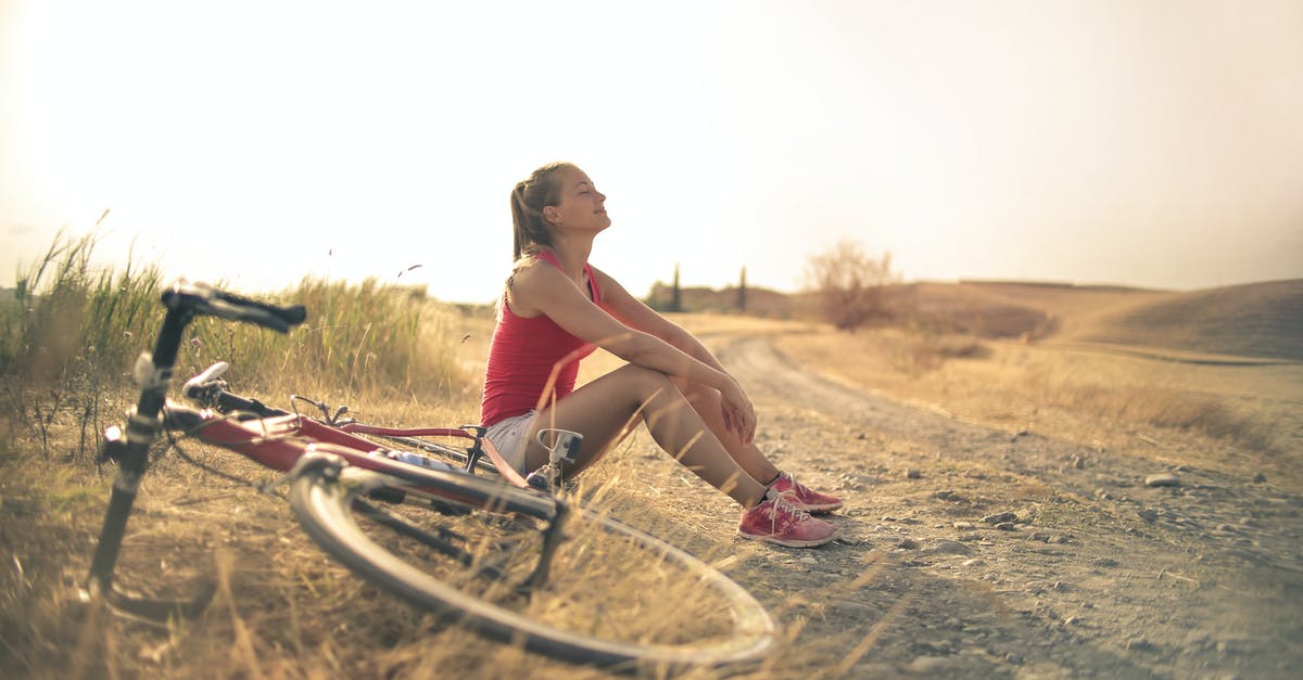 Who is the woman on the bicycle who rides up to Uncle Rico? - Full body of female in shorts and top sitting on roadside in rural field with bicycle near and enjoying fresh air with eyes closed