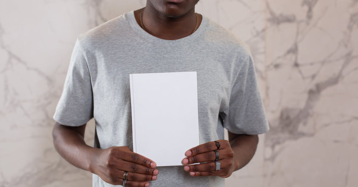Who made this Ant-Man promotional material? - Unrecognizable African American male in casual gray t shirt standing with white mock up notepad in hands near wall in light room