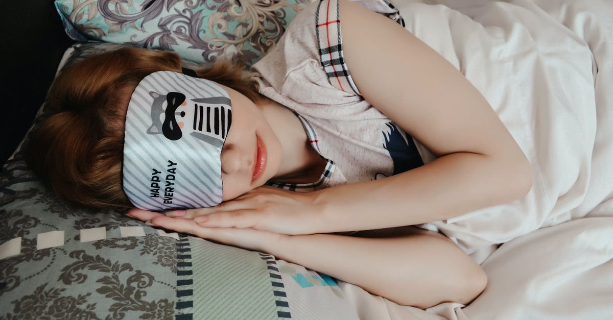 Who placed the mask on the bed in Eyes Wide Shut? - Anonymous female covering eyes with sleep mask taking nap while lying on bed under blanket in cozy bedroom at home