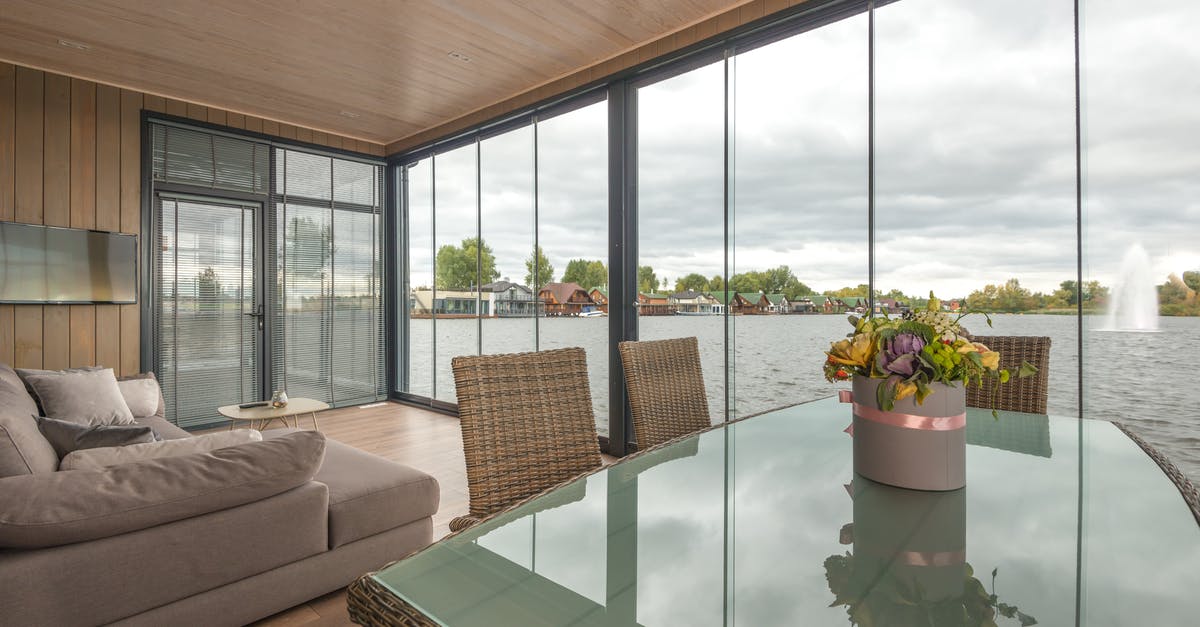 Who really designed The Lake House and under what considerations? - Elegant flowers bouquet placed on table with glass top in contemporary house with soft sofa and glass walls located on lake under overcast sky