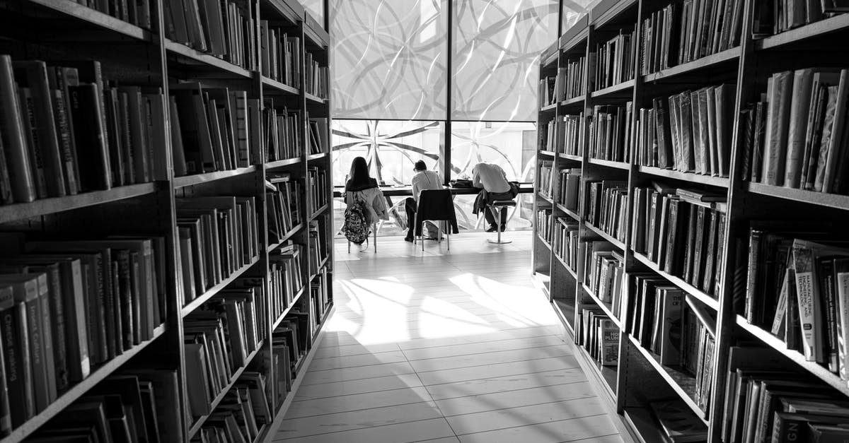 Who recruited this many students without informing Bartleyby? - Black and white back view of distant anonymous group of visitors studying at table in library with assorted books on bookshelves