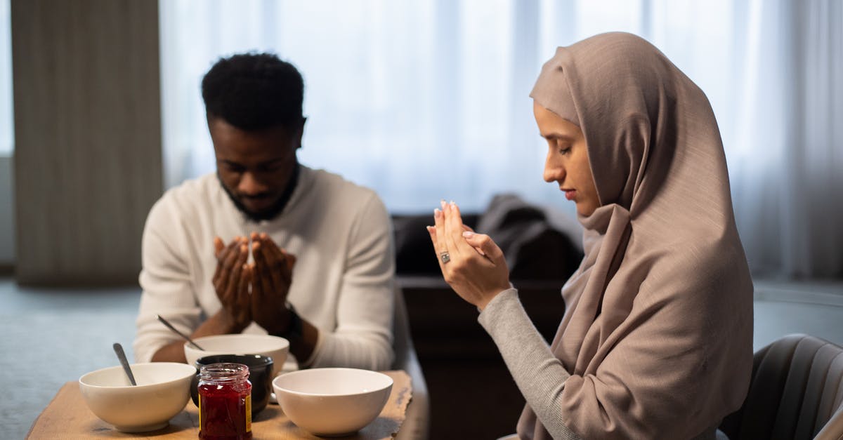 Who was making silent calls? - Multiethnic couple praying at table before eating