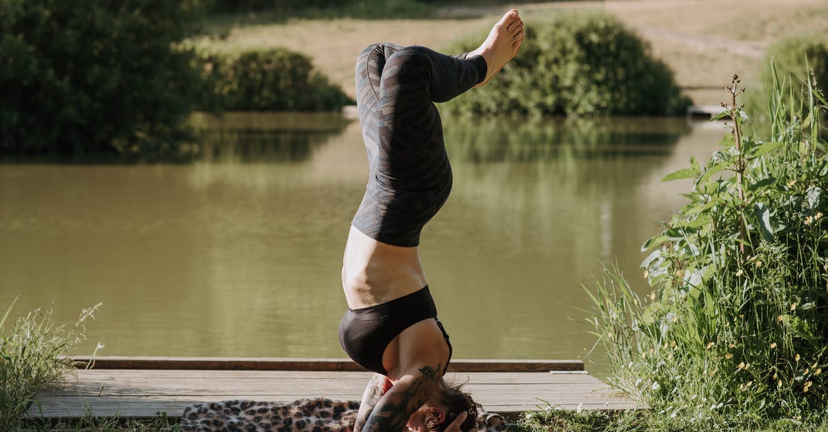 Who was the body in the lake? - Unrecognizable woman standing on head while practicing yoga against pond