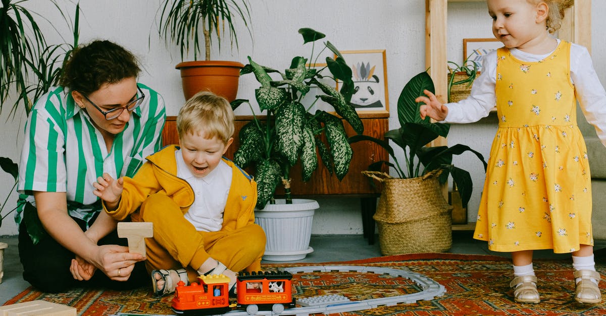 Who was the lady mending the toy at the end? - Mom and adorable little brother and sister in casual wear gathering in cozy living room during weekend and having fun together while playing with plastic railway