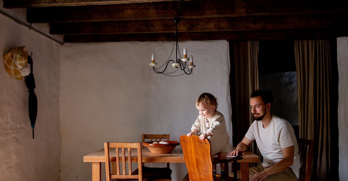 Who was the old guy in room 353? - Cheerful cute little daughter spending time together with bearded father in casual wear inside aged room near wooden dinner table with wooden chairs at daytime
