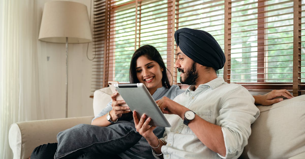 Whose phone numbers are shared in Indian Movies? - Optimistic young Indian couple using tablet and smartphone during weekend