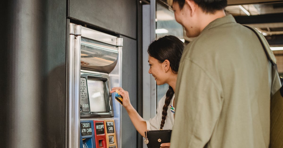 Why are they distributing money to the customers at the ticket collecting point? - Content couple using ticket machine in underground
