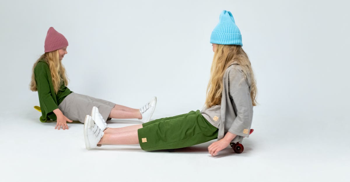 Why are twins often cast for young roles? - Woman in Green Jacket and Blue Knit Cap Sitting on White Floor
