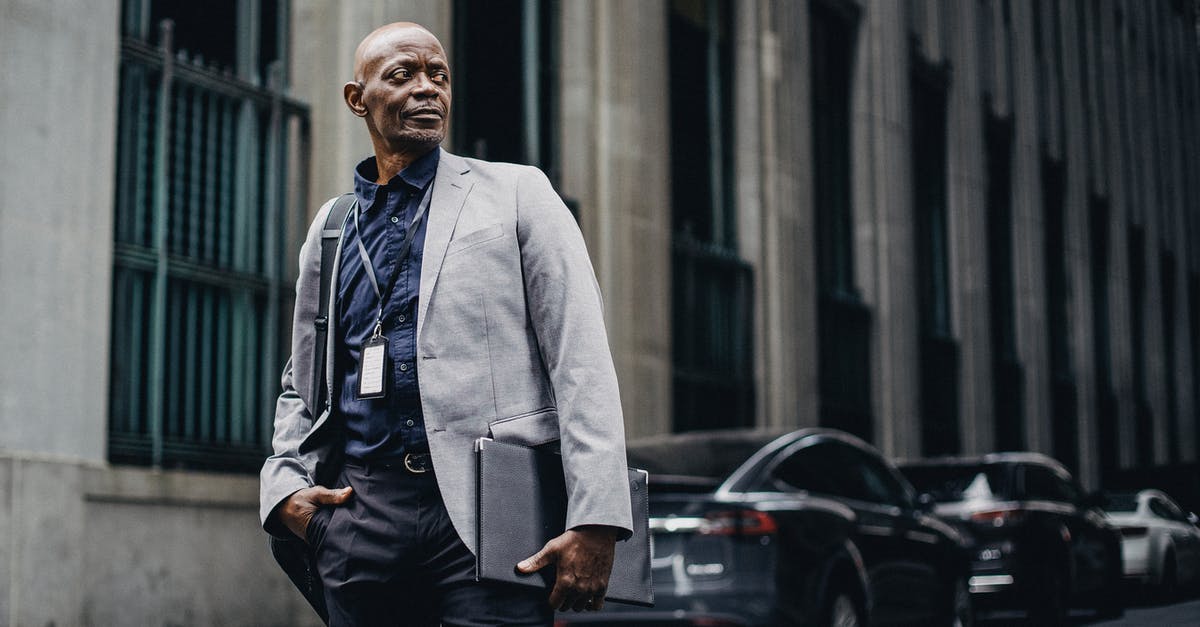 Why authorities didn't change retina scan of building after CEO got kidnapped? - Serious adult African American businessman in formal suit standing with hand in pocket on urban street and looking away thoughtfully