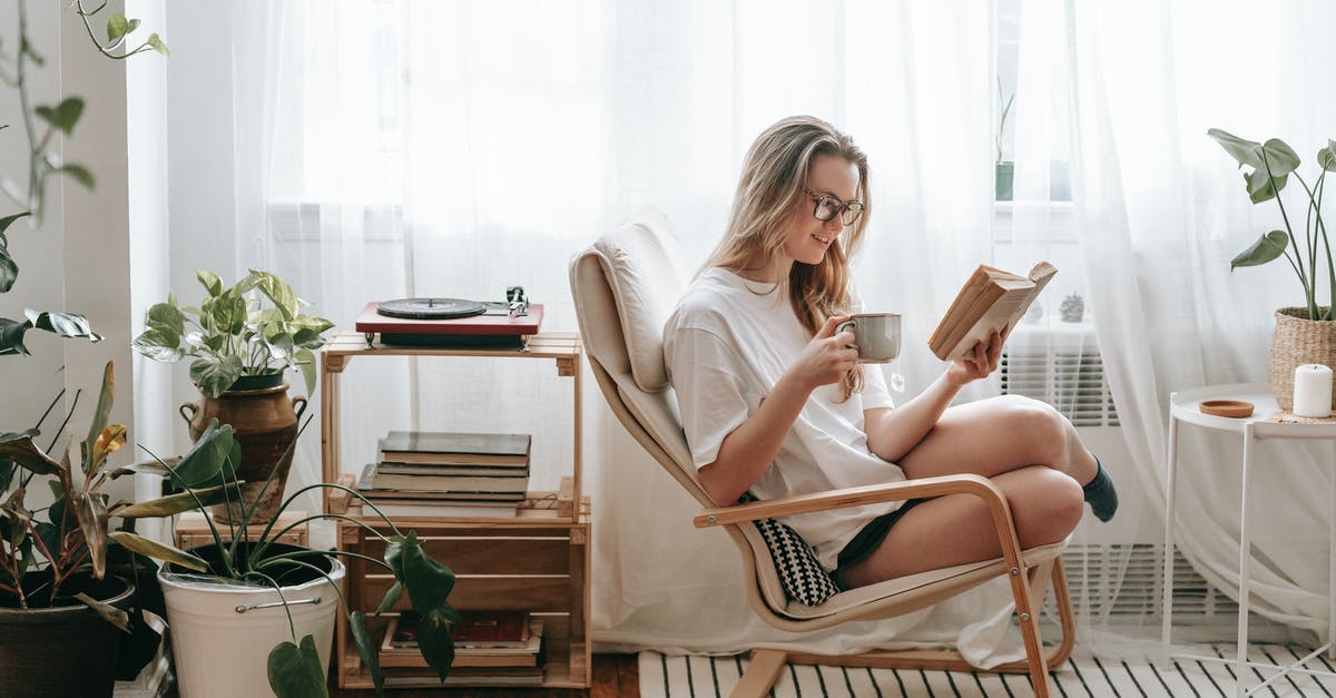 Why can't Jim get a better coffee/breakfast? - Cheerful young female in eyeglasses with cup of beverage reading textbook in armchair between potted plants in house room