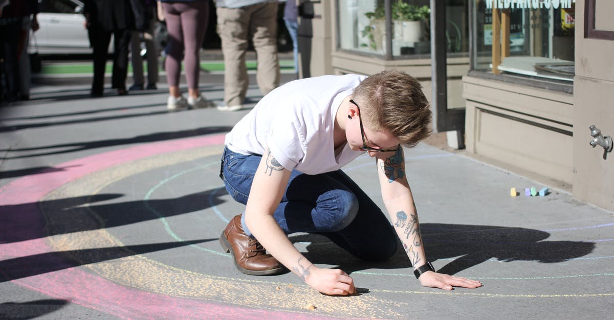 Why can't people see colors in "The Giver"? - Photo of a Man in White T-Shirt Coloring on Gray Pavement Next to a Building 