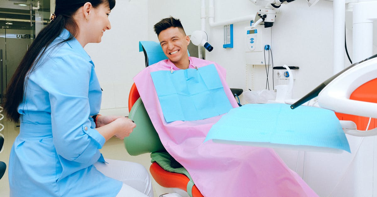 Why can't they visit each other? - Cheerful ethnic male patient sitting in dental chair in clinic