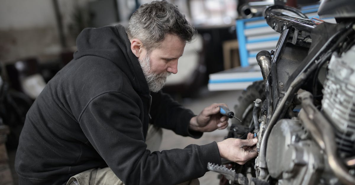 Why couldn't Cage and Rita take a military helicopter to reach the dam? - Bearded man fixing motorcycle in workshop