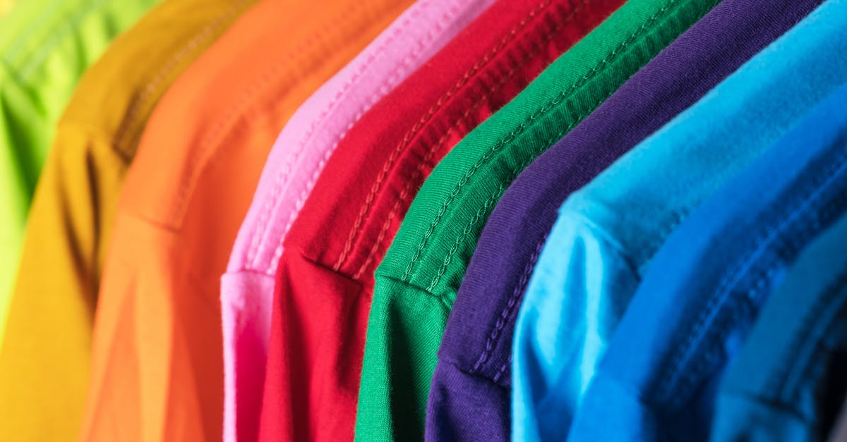 Why couldn't they live with different appearances in "What happened to Monday"? - Closeup of multicolored vibrant cotton t shirts hanging in row in modern wardrobe