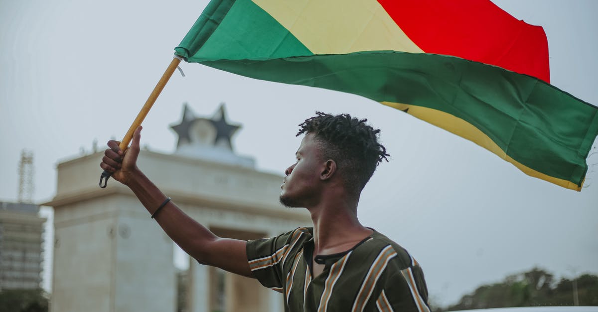 Why did Anakin betray the republic despite promising he won't - African male with dreadlocks raising flag of Ghana country with colorful stripes while looking away in town